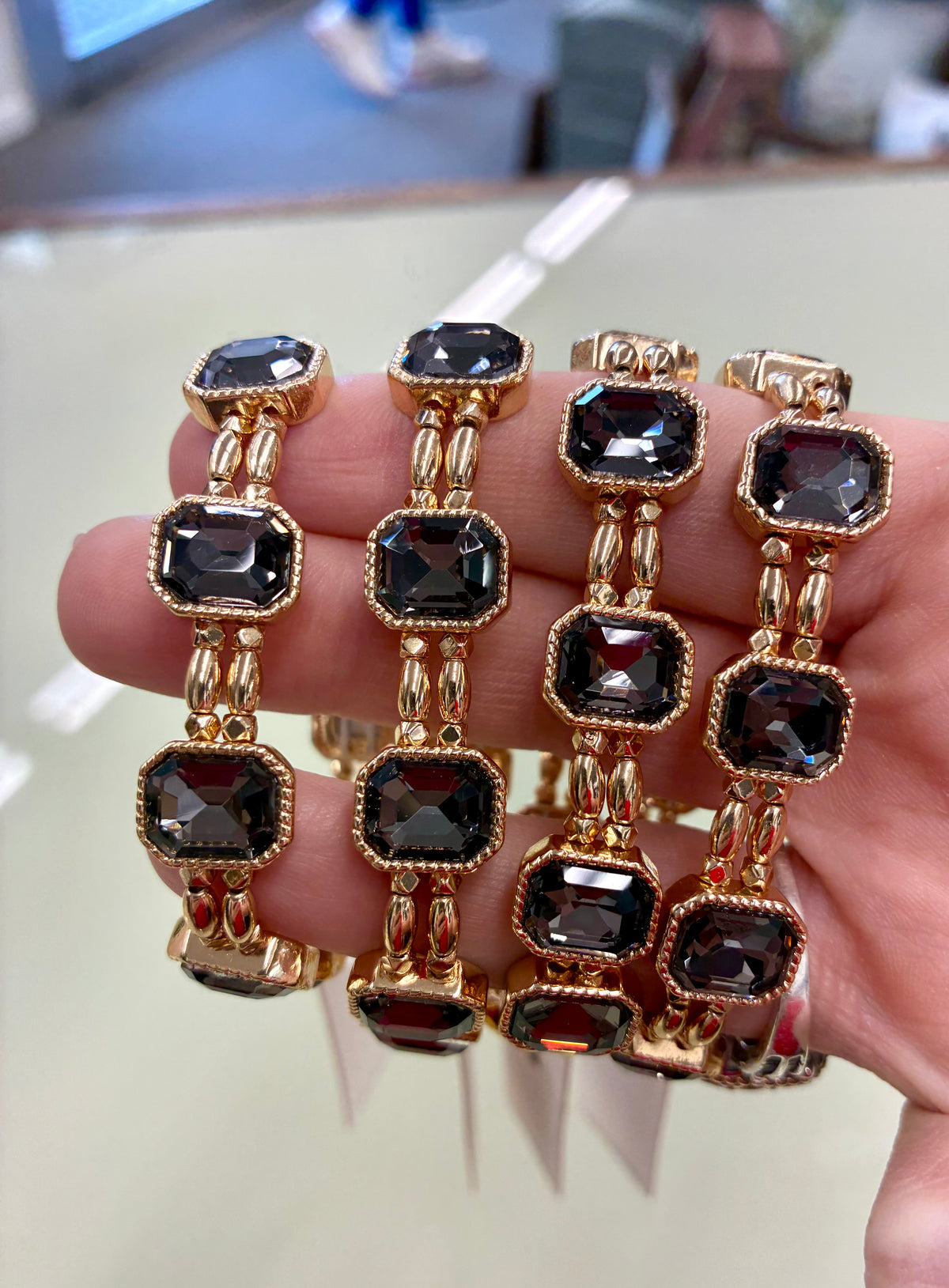 Gold-tone stretch bracelet featuring faceted, emerald-cut dark grey crystals