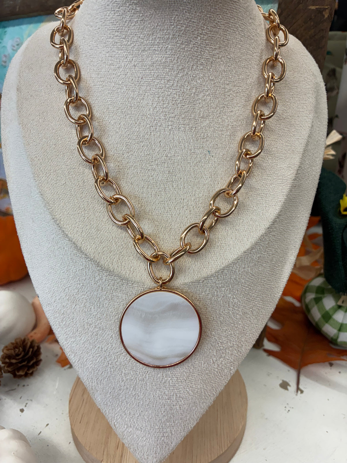 Chunky gold-tone link chain necklace featuring a large, round white pendant