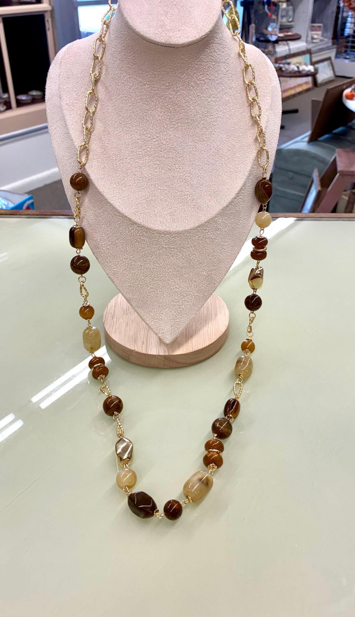 Multi-strand gold-tone chain necklace featuring polished caramel, amber-colored, and beige natural or resin beads.