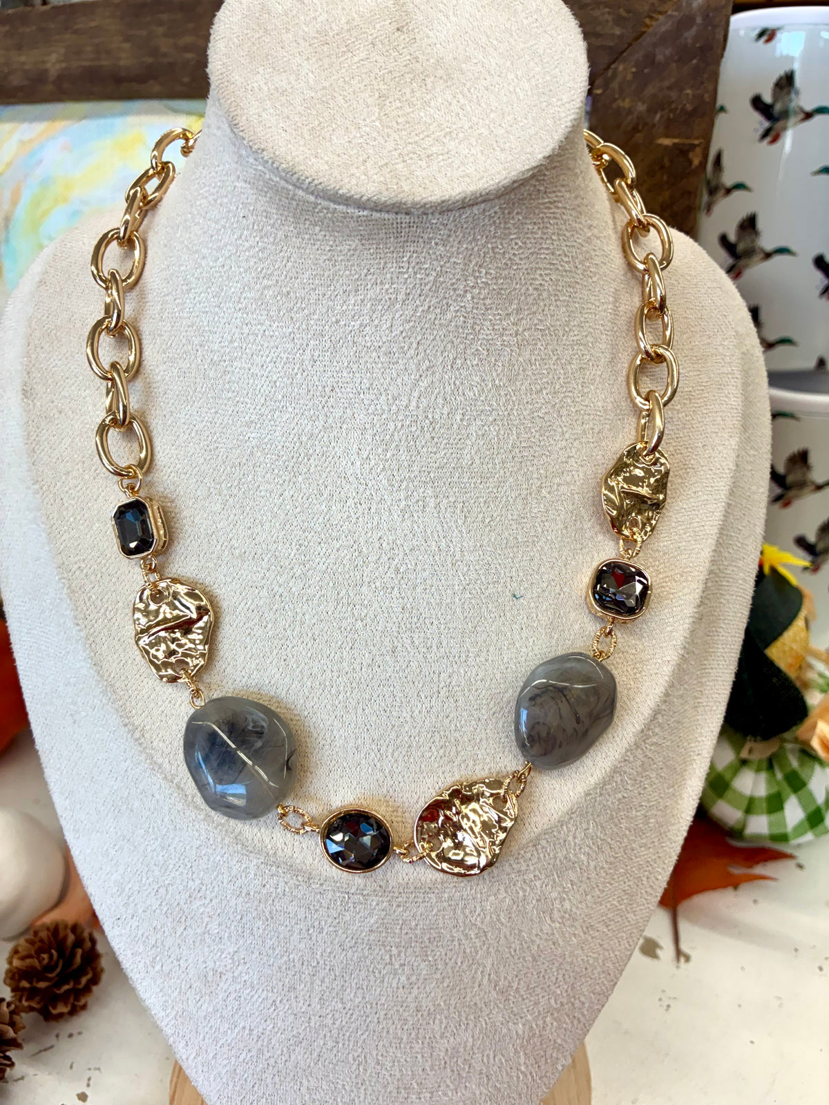 Gold chunky link necklace featuring smooth grey stone beads and textured golden accent pieces