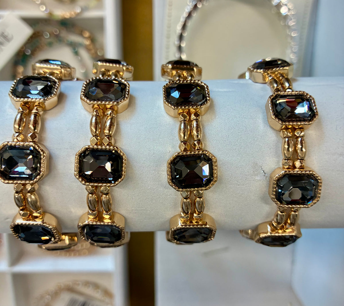 Gold-tone stretch bracelet featuring faceted, emerald-cut dark grey crystals