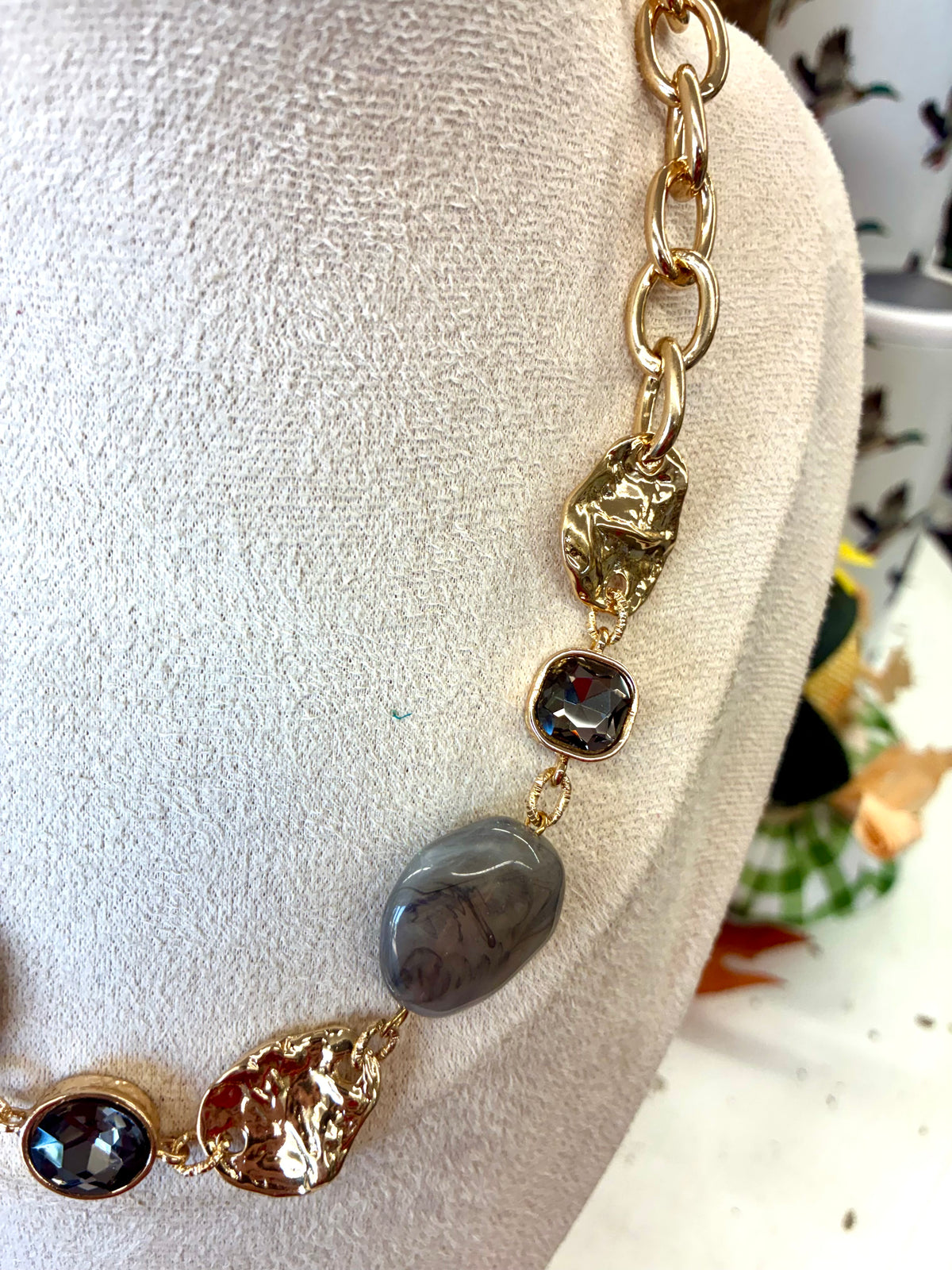 Gold chunky link necklace featuring smooth grey stone beads and textured golden accent pieces