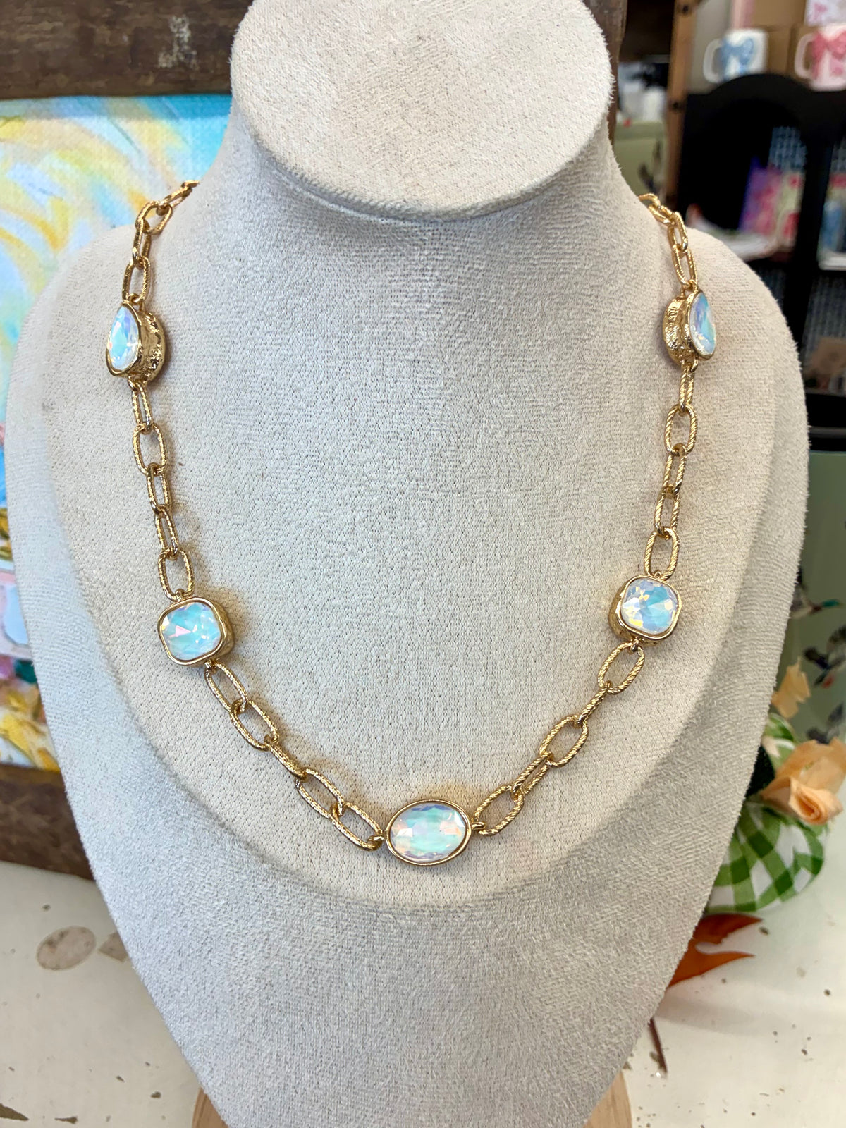 Gold toned link chain necklace featuring iridescent, opal-like station stones set in bezels