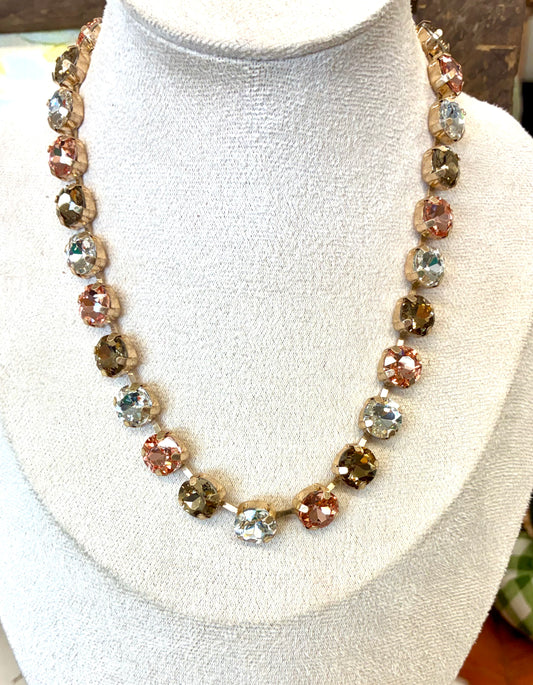Multi-stone crystal collar necklace featuring faceted round stones in alternating metallic, rose, and smoky tones / Gold-tone linear drop earrings featuring a cascading gradient of sparkling yellow, olive, and amber-toned crystal stone.