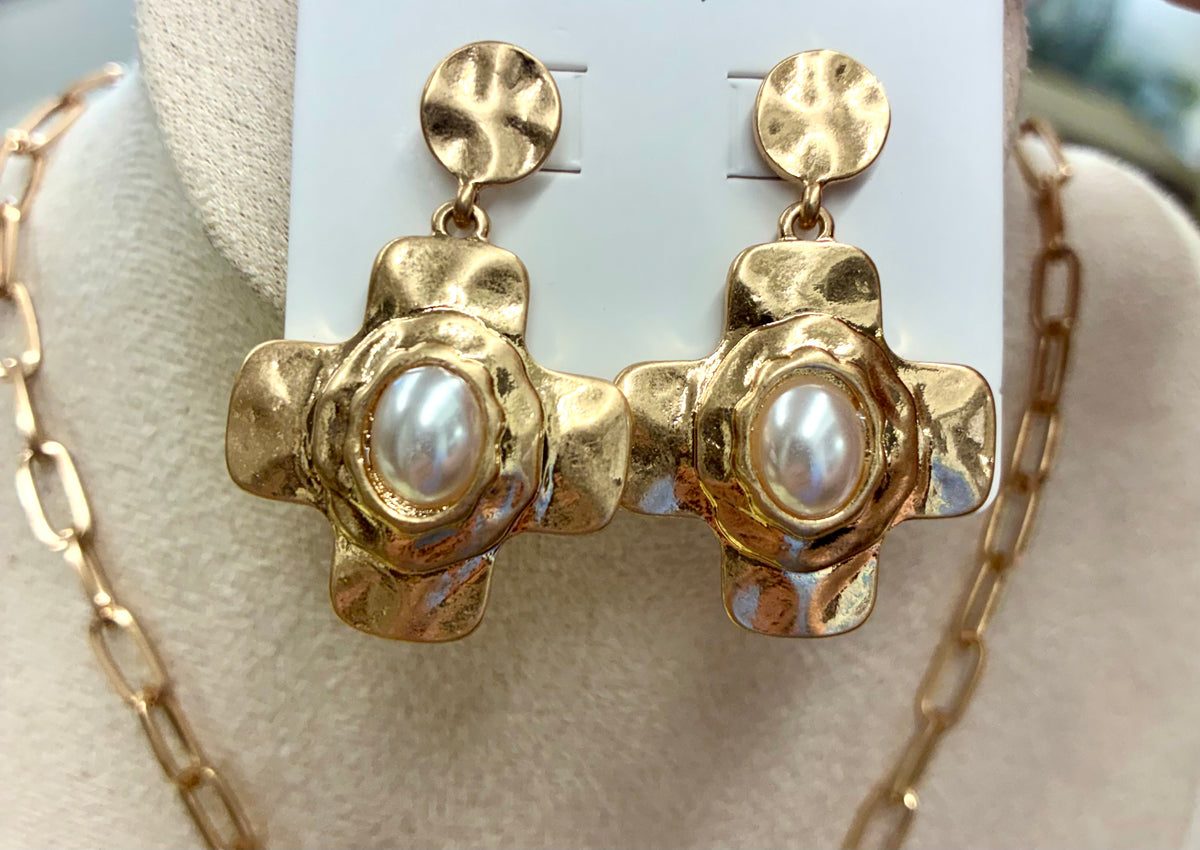 Gold-tone hammered cross necklace and matching earrings sold separately set featuring a central pearl accent and a toggle clasp.